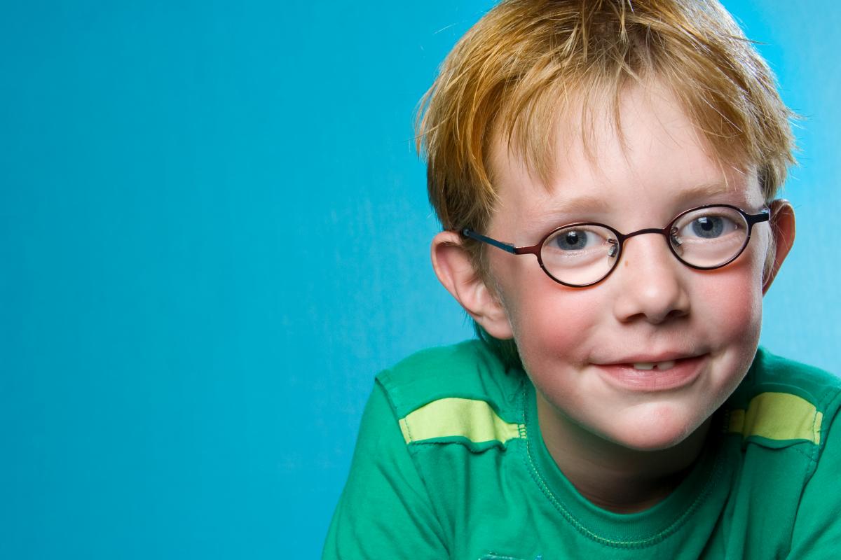 Jongen_met_oranje_haren_en_bril_bij_met_een_lichtblauwe_achtergrond