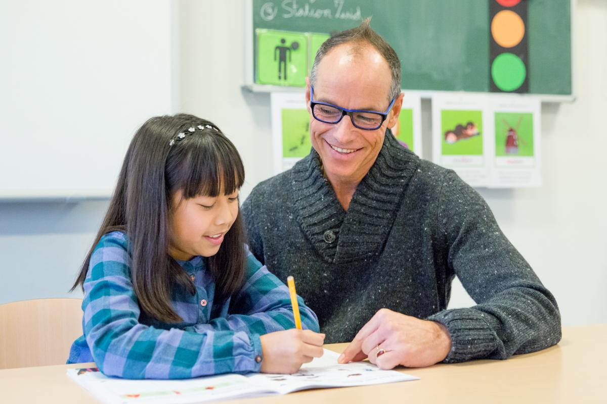 Leeraar_en_leerling_werken_samen_in_een_werkboek_in_de_klas.