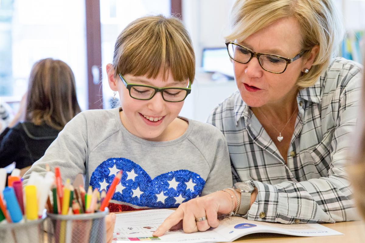 Meisje_uit_groep_7_krijgt_uitleg_over_haar_werkboek_door_haar_juf.
